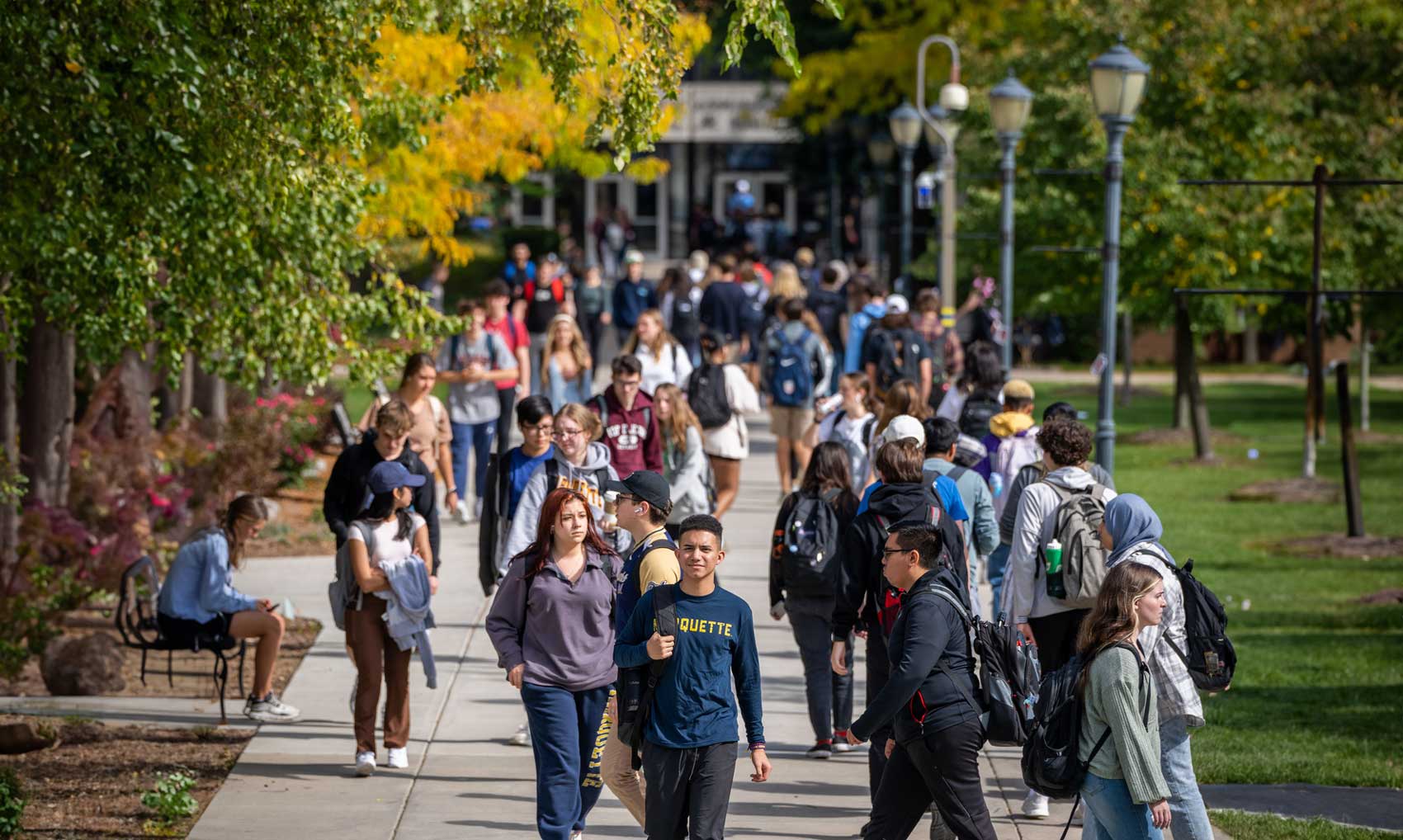 crowd of students walking across campus sunny day