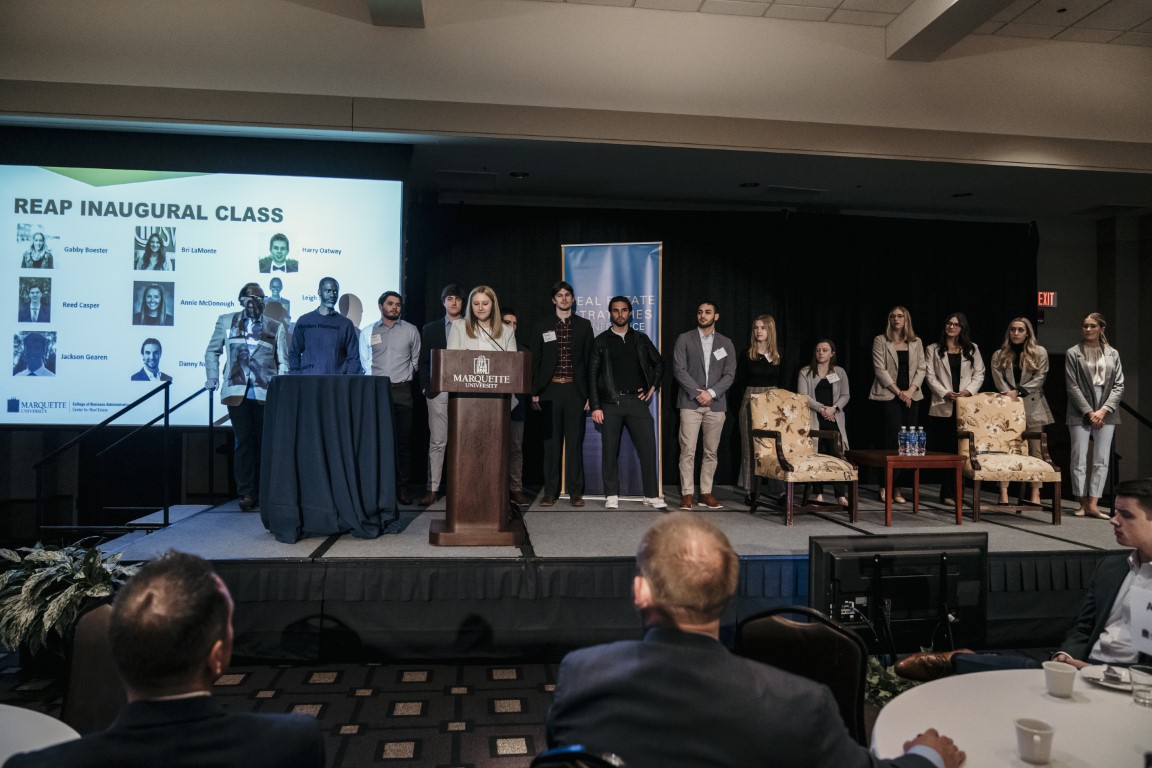 A crowd of students stand on a stage at the Real Estate Strategies Conference