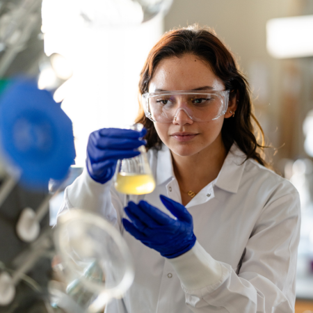 student analyzing a glass lab beaker full of liquid