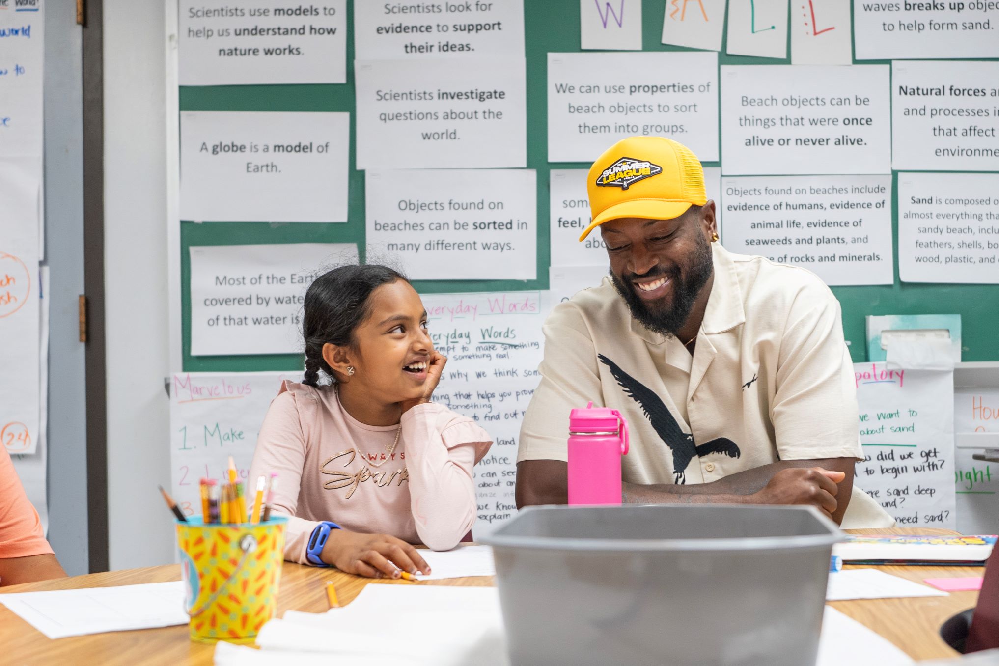 young girl and dwyane wade at table in classroom