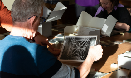 man at a library table examining an archival photograph of the chapel