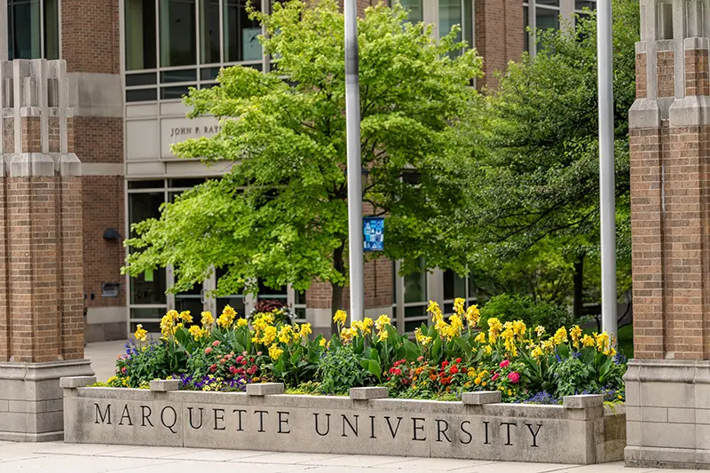 Marquette University sign and flowers in front of Raynor Library