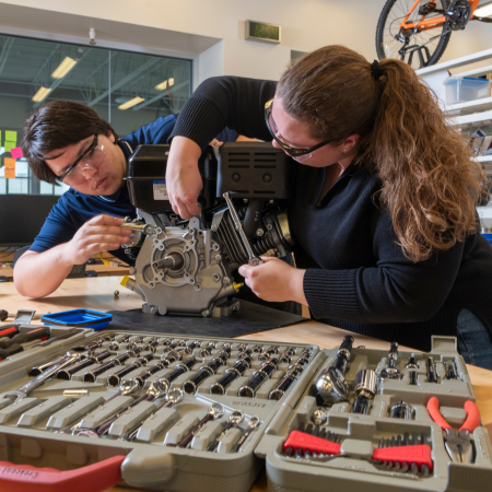 two students collaborating on an engine