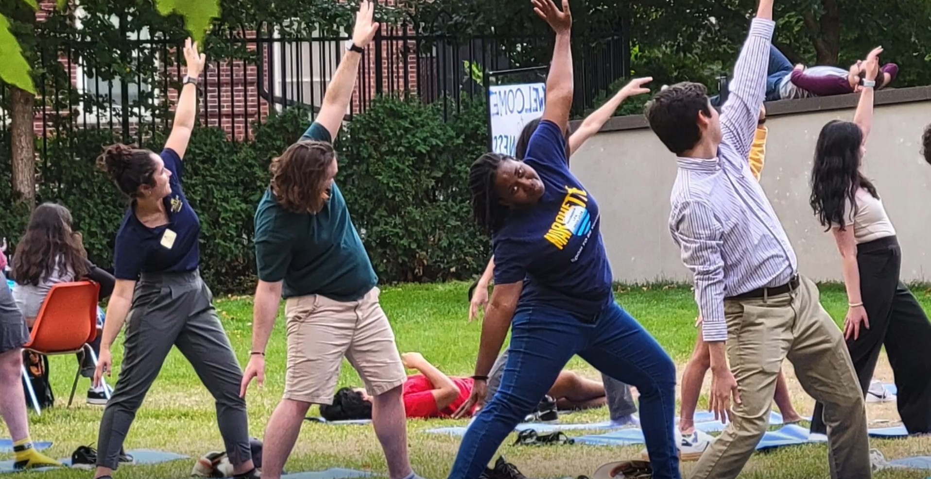 group of young adults practicing yoga outside on a grassy field