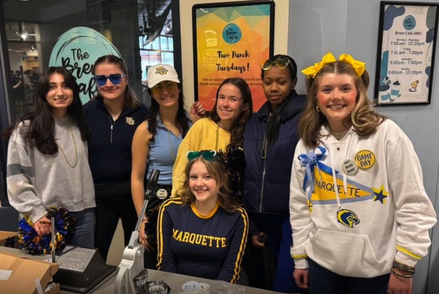 a group of young adults posing behind a table with a button maker on it